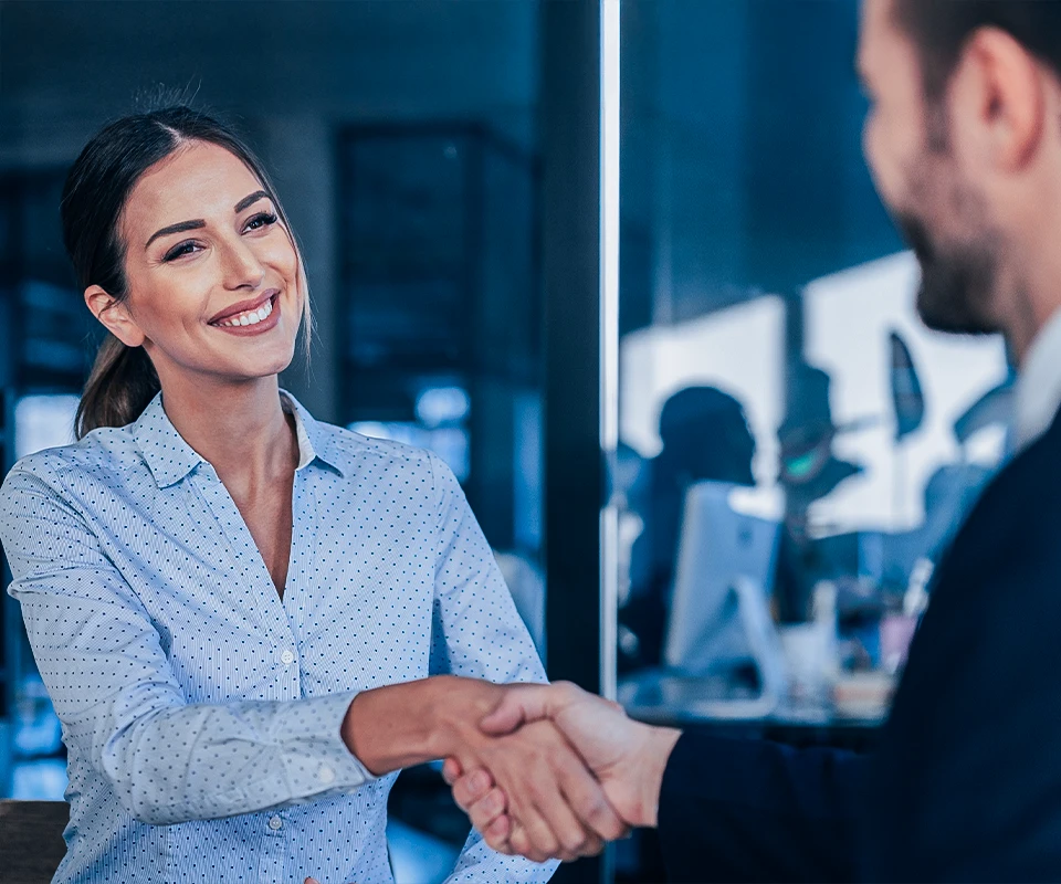 Duas pessoas apertando as mãos em um escritório, simbolizando acordo financeiro e emissão de Nota Comercial (NC) com apoio da MakeValue