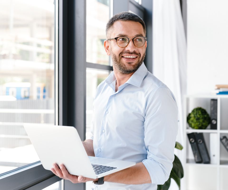 Homem segurando um notebook, ilustrando os benefícios da API de cobrança e a otimização de processos financeiros.